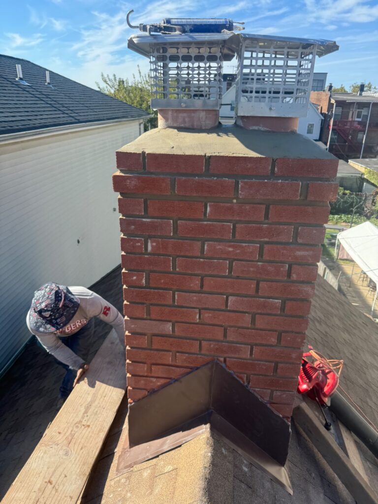 Same chimney after masonry rebuilding with caps and flashing