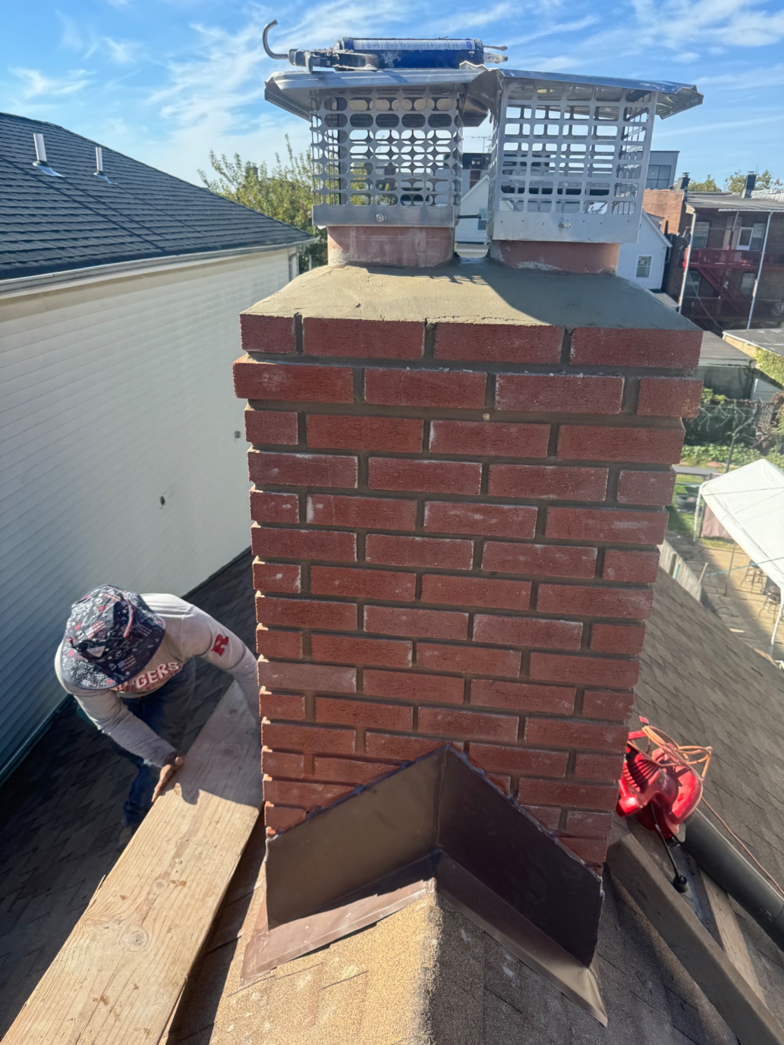 Chimney crown and protective metal caps above rebuilt brickwork